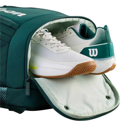Green tennis bag with a white and green Wilson tennis shoe inside on a white background